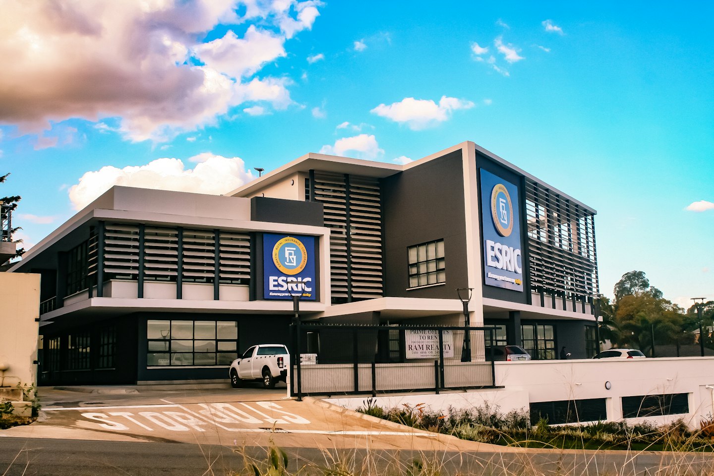 Edificio de oficinas moderno con cartel de alquiler y camión aparcado.