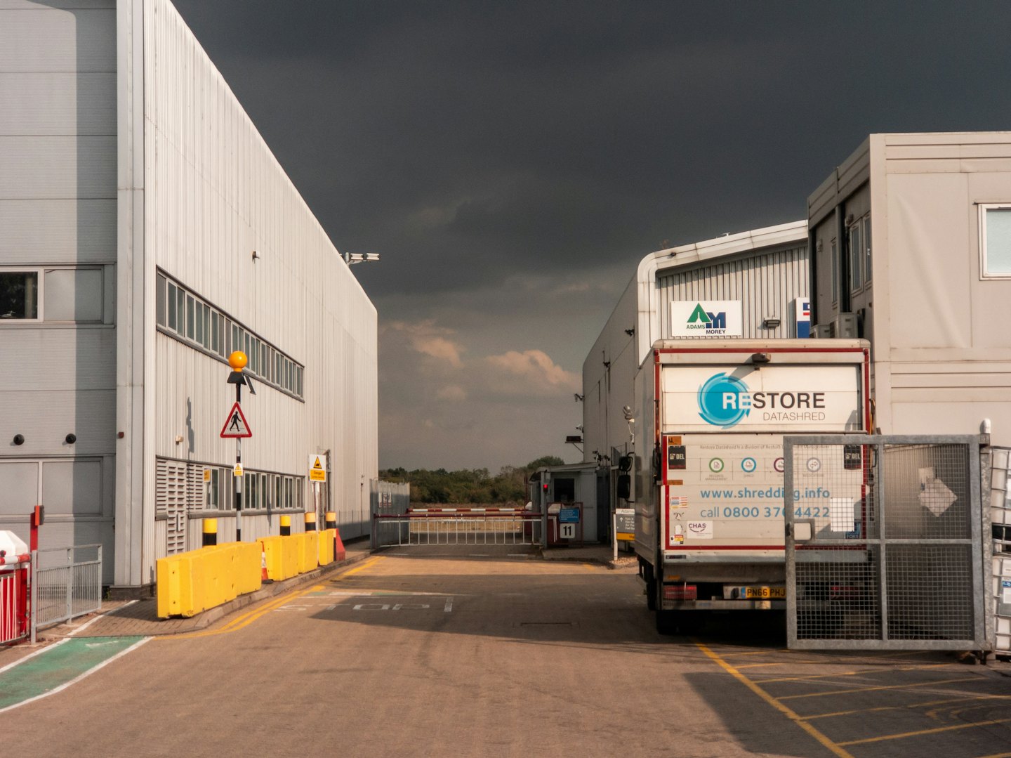 Camión blanco de trituración de datos estacionado en la entrada de una instalación industrial.